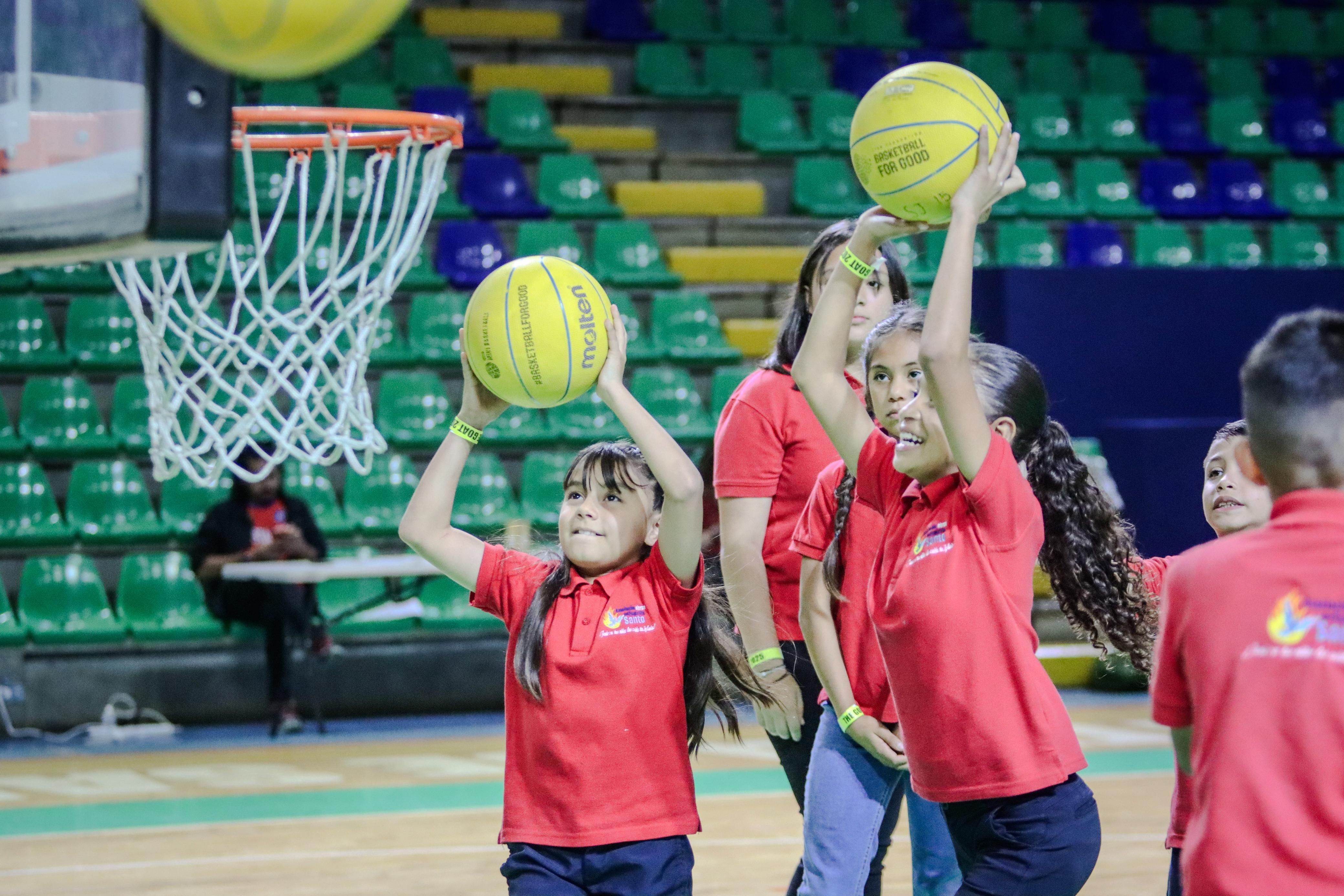 Niñas practicando tiros a canasta en el pabellón durante el torneo
