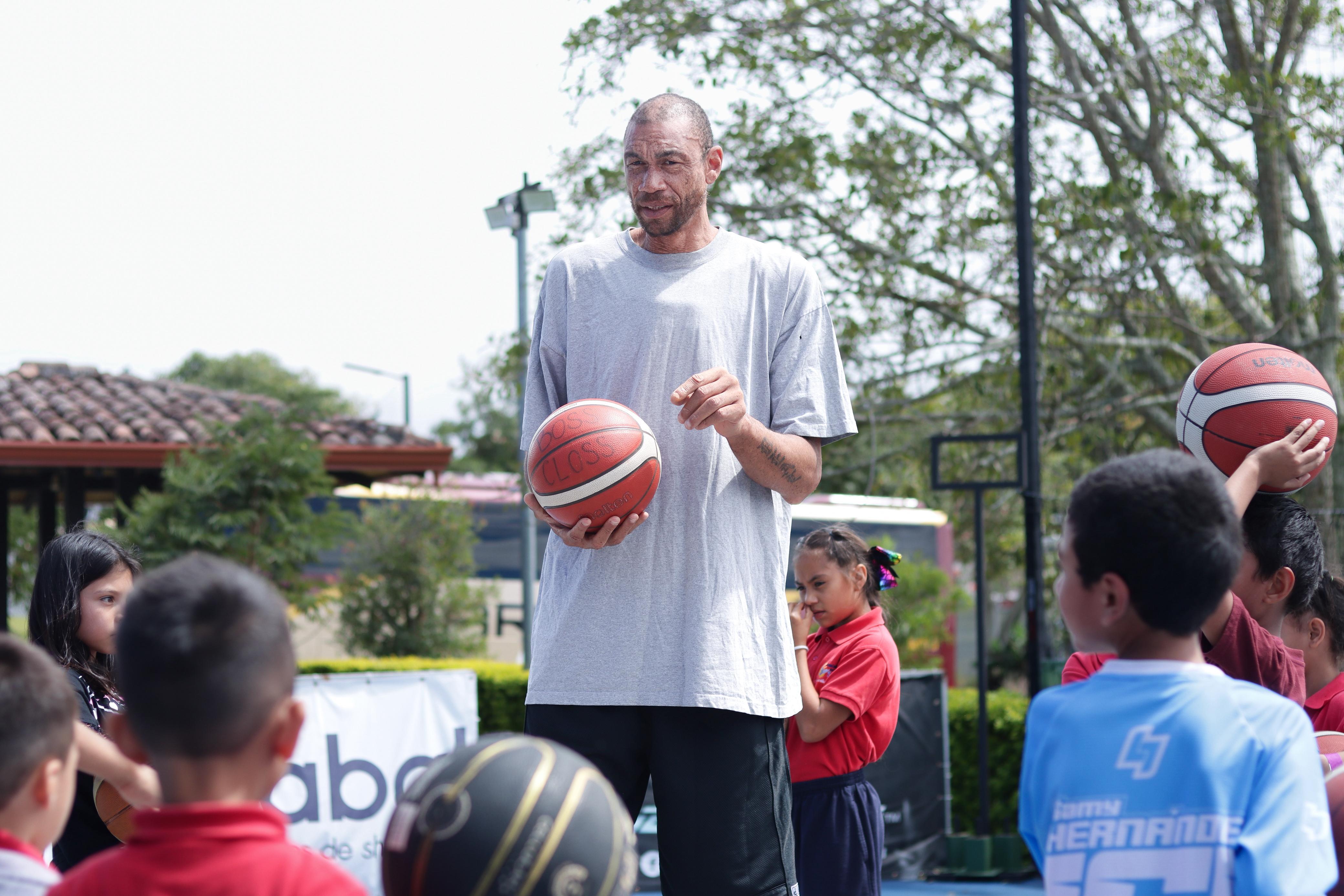 Entrenador profesional dirigiendo un clinic de baloncesto con los participantes
