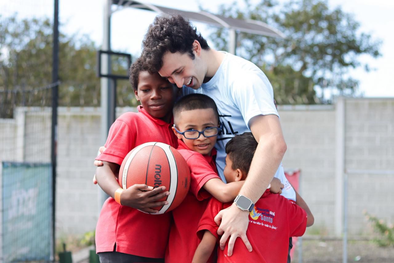 Mentor abrazando a varios niños tras una sesión del programa GOAT